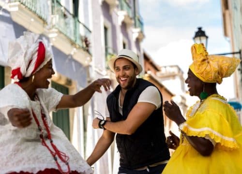 um jovem mochileiro dancando com duas baianas